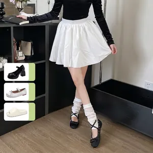 High-waist white pleated mini skirt styled with ballet mesh leg warmers and Mary Janes