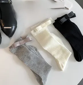 Detailed view of ribbed cotton crew socks with satin bow accents in grey white and black