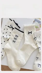 Detailansicht weißer Socken mit schwarzen Schleifen und Wellensaum aus Baumwolle