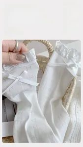 Close-up of white mesh mid-calf socks with lace trim and sweet bow detailing