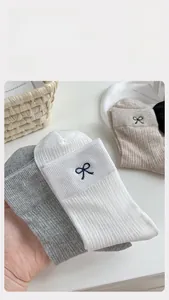 Macro shot of vertical rib-knit texture and elegant bow embroidery on cotton socks