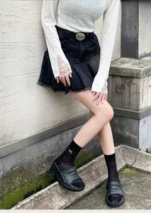 Detail of black mid-calf socks with vertical ribs and a white bow accent on the cuff