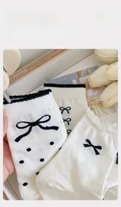 Detail weißer Baumwollsocken mit schwarzen Schleifen und elastischem Komfortbund