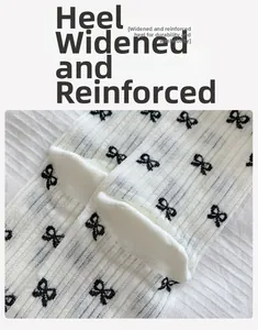 Detail of reinforced heel on white ribbed socks featuring black bow patterns for women
