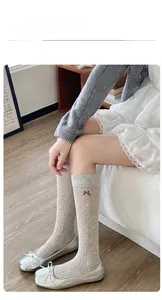 Detail of grey mesh knee-high sock with ribbed cuff and delicate black bow accent