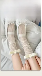 Detail of cream rib-knit mid-calf socks with elegant satin bow accents and texture