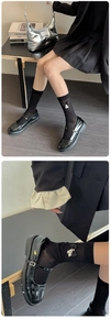 Close-up of black ribbed mid-calf socks with white bow and pearl details on Mary Jane shoes