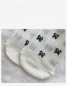 Detail of white mesh socks with black bow patterns and flat toe seam for girls