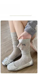 Detail of light gray ribbed calf socks with black bow embroidery and ballet flats