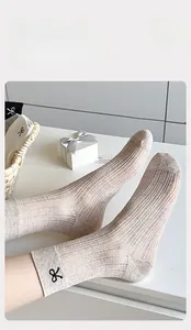 Detail of breathable mesh mid-calf socks featuring black embroidered bow and knit texture
