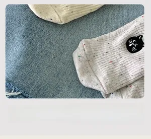 Detailed macro view of cream knitted sock with cute cat embroidery and colorful dots
