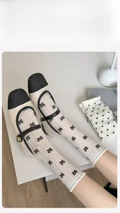 Detail of white rib-knit socks with black bow embroidery and Mary Jane shoes