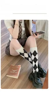 Detailed view of black and white argyle over-knee socks on model for vintage college style