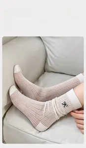 Detail of pink mesh socks featuring black bow embroidery and white ribbed cuffs