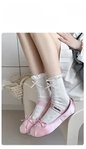 Detailed view of white lace crew socks featuring mesh texture and delicate bow patterns