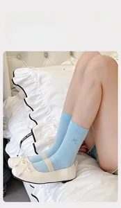Close-up of light blue cotton socks with delicate bow embroidery detail on the side
