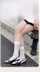 Close-up of white ribbed crew socks featuring delicate bee embroidery and sheer texture