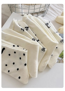Nahaufnahme cremefarbener Baumwollsocken mit schwarzen Punkten und zarten Schleifenmustern