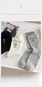Close-up of knit cotton socks featuring delicate bow embroidery and ruffled edge trim