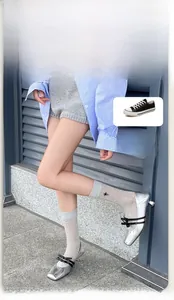Detail of light grey ribbed socks featuring black insect embroidery and bow shoes