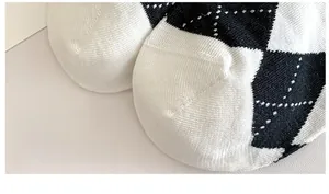 Macro detail of seamless toe stitching on black and white argyle pattern cotton socks