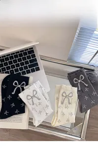 Detail of four-color knit socks with bow and rhinestone accents on a glass table