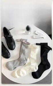 Detail of cotton mid-calf socks with silky bows and vertical stripes on a white table