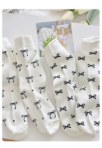 Detail von cremefarbenen Baumwollsocken mit schwarzen Schleifenmustern und Deko