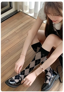 Detail of argyle pattern knee-high socks in black and brown paired with Mary Jane shoes
