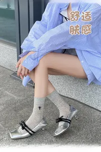 Silver pointed-toe kitten heels with black bows and studs paired with grey crew socks
