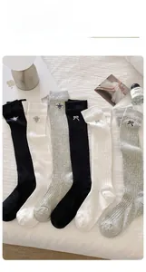 Detail of mesh bow embroidered socks in black white and grey on a white sheet