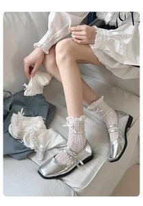 Detail of white mesh crew socks with lace trim and bow paired with silver Mary Jane shoes