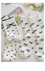 Detail von cremeweißen Baumwollsocken mit schwarzen Schleifenmustern und Wellenrand