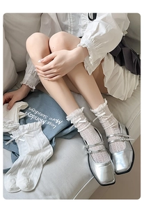 Detail of white lace mid-calf socks with silk bows paired with silver Mary Jane shoes