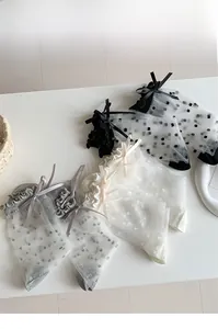 Detail von Netzsocken mit süßen Schleifen und Polka Dots in Schwarz, Weiß und Grau