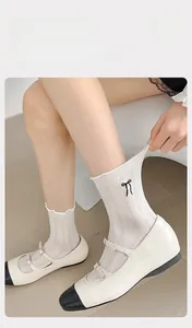 Detail of off-white ribbed crew sock with elastic wavy ruffle cuff and bow embroidery
