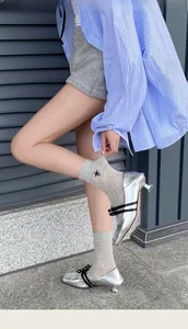 Detail of grey crew socks featuring insect embroidery paired with silver Mary Jane shoes