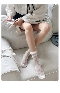 Close-up of white lace mesh socks with delicate ribbon bow and ruffled edges
