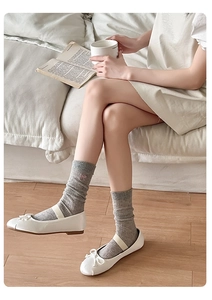Detail of light gray ribbed crew socks with pink bow embroidery and white Mary Jane shoes