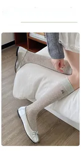 Detailed close-up of beige ribbed knee socks featuring black bow embroidery and ballet flats