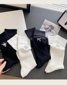 Close-up of cotton ribbed socks with delicate bow and spider embroidery in black and white