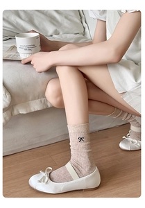 Detail of oat-colored knitted socks with black bow embroidery and Mary Jane shoes