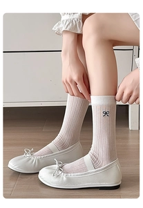 Close-up of white slouch socks with black bow embroidery and ballet flats