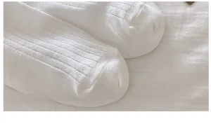 Close-up of white mesh knee-high socks showing detailed stitching and vertical texture