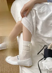 Detail of white ribbed mesh socks with satin bow accent and vertical stripe texture