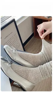 Detail showing elastic light khaki ribbed socks paired with silver ballet flats and bow