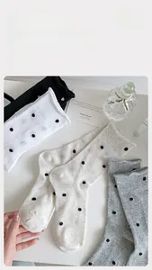 Detail of polka dot crew socks in black, white, and grey with ruffle hem edges