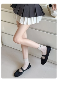 Detail of white mesh mid-tube socks with delicate black bow embroidery and Mary Jane shoes