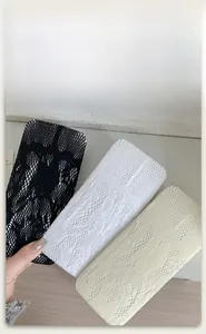 Détail de la texture dentelle des chaussettes montantes en noir, blanc et beige