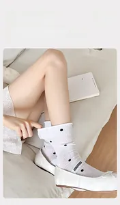 Close-up of breathable white mesh socks with black polka dots and rolled cuff details